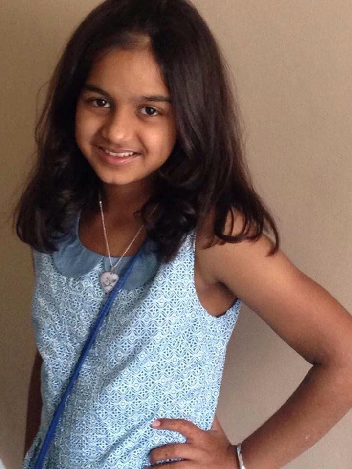 Aalia Shameer Mahomed as a child in a blue dress